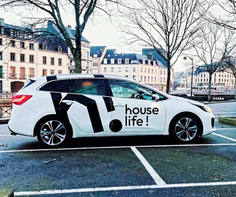 Voiture électrique avec logo House Life, stationnement urbain, environnement moderne.